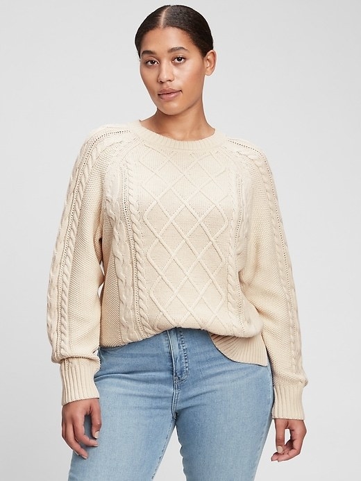 model wearing a white cable-knit sweater