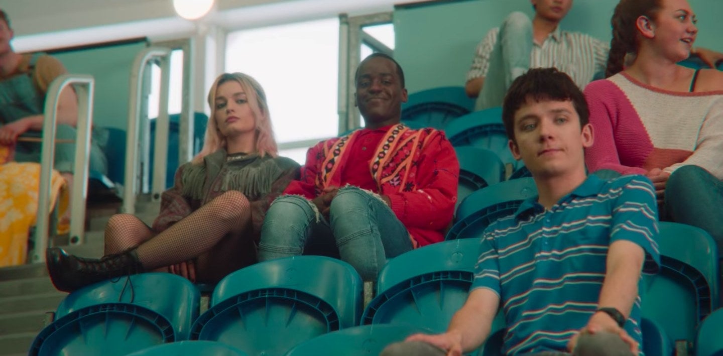 Otis, Maeve, and Eric sitting in the stands of their school&#x27;s pool room in &quot;Sex Education&quot;