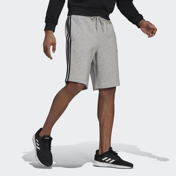 model in knee-length light gray fleece training shorts and black sneakers