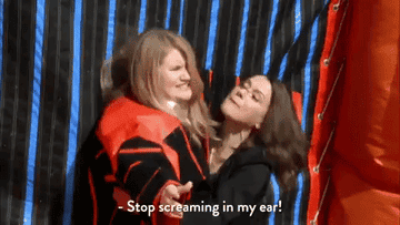 Two girls mouthing, &quot;stop screaming in my ear!&quot;