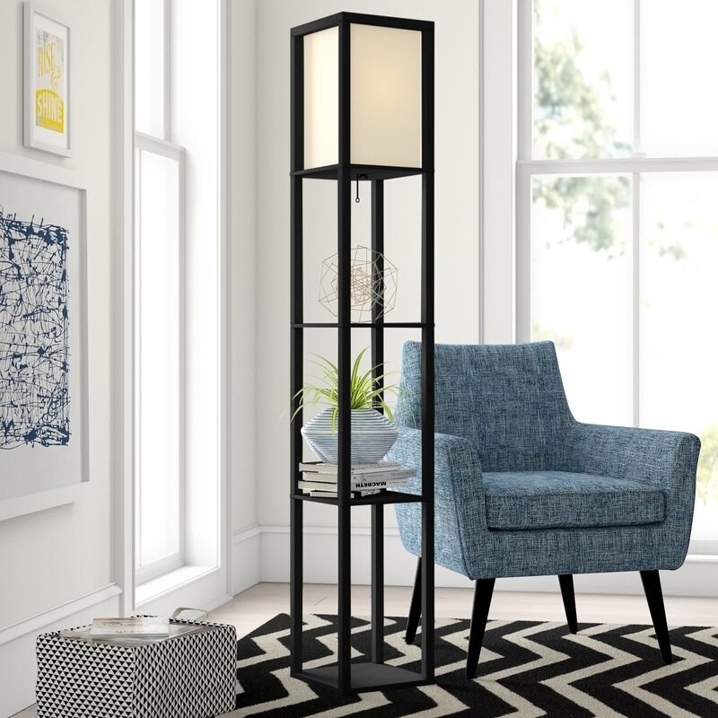 A black lamp in a black and white room with blue chair