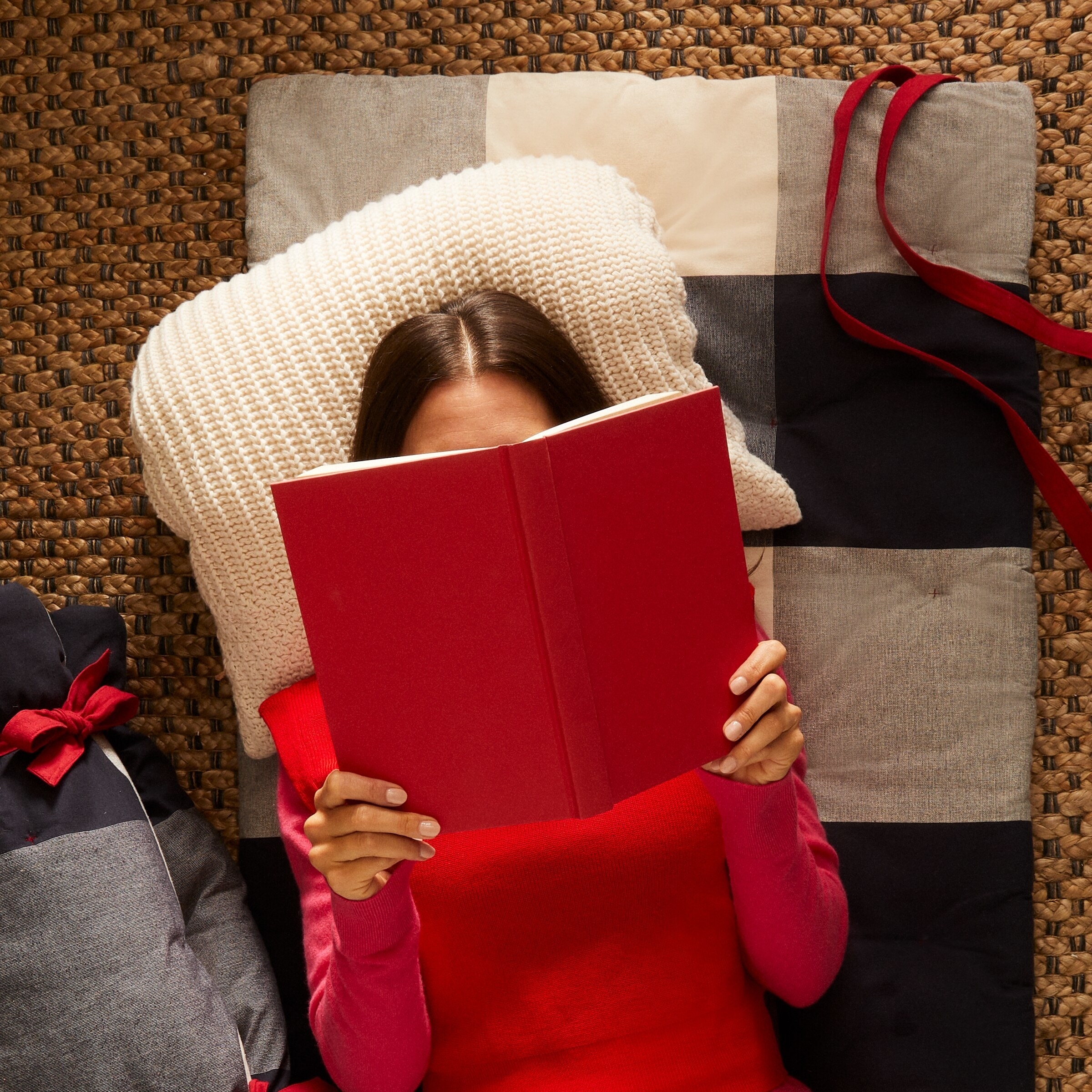 a person reading a book on the plaid mat