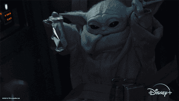 baby yoda holding a can and waving hands in the air