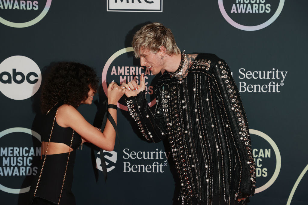 Casie and Machine Gun Kelly making a pinky promise on the red carpet