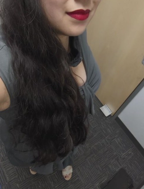 A selfie of a woman from her mouth down showing her dark, wavy hair