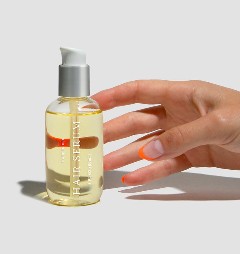 model reaching for pump bottle of translucent yellow hair serum