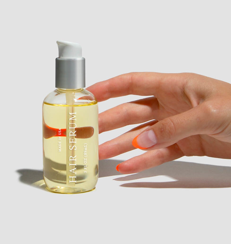 model reaching for pump bottle of translucent yellow hair serum