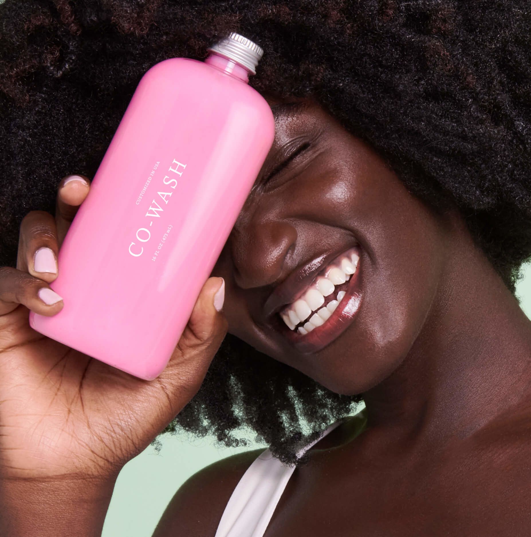 model holding pink bottle of co-wash