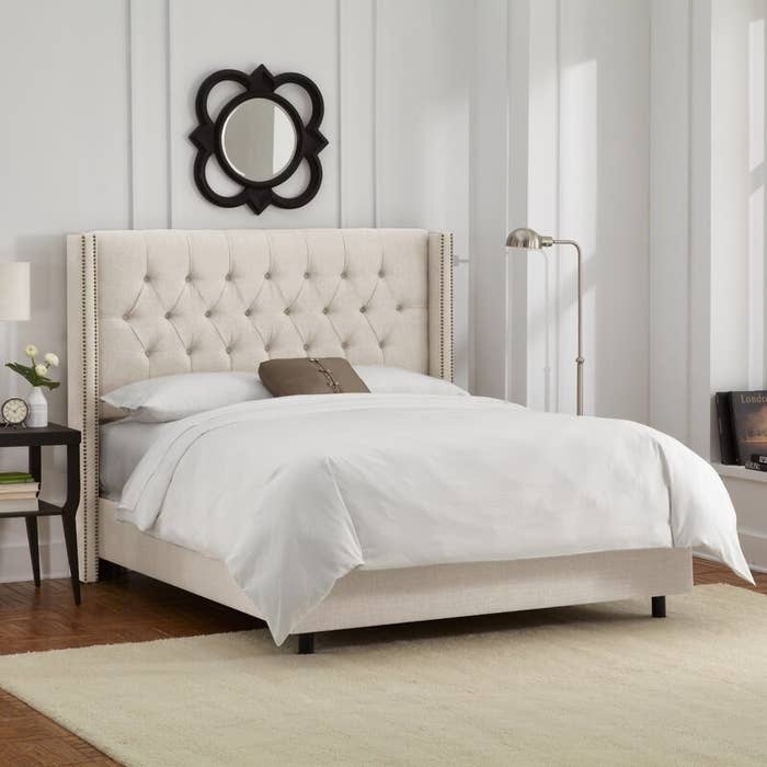 Beige tufted bed frame with headboard, white bedding