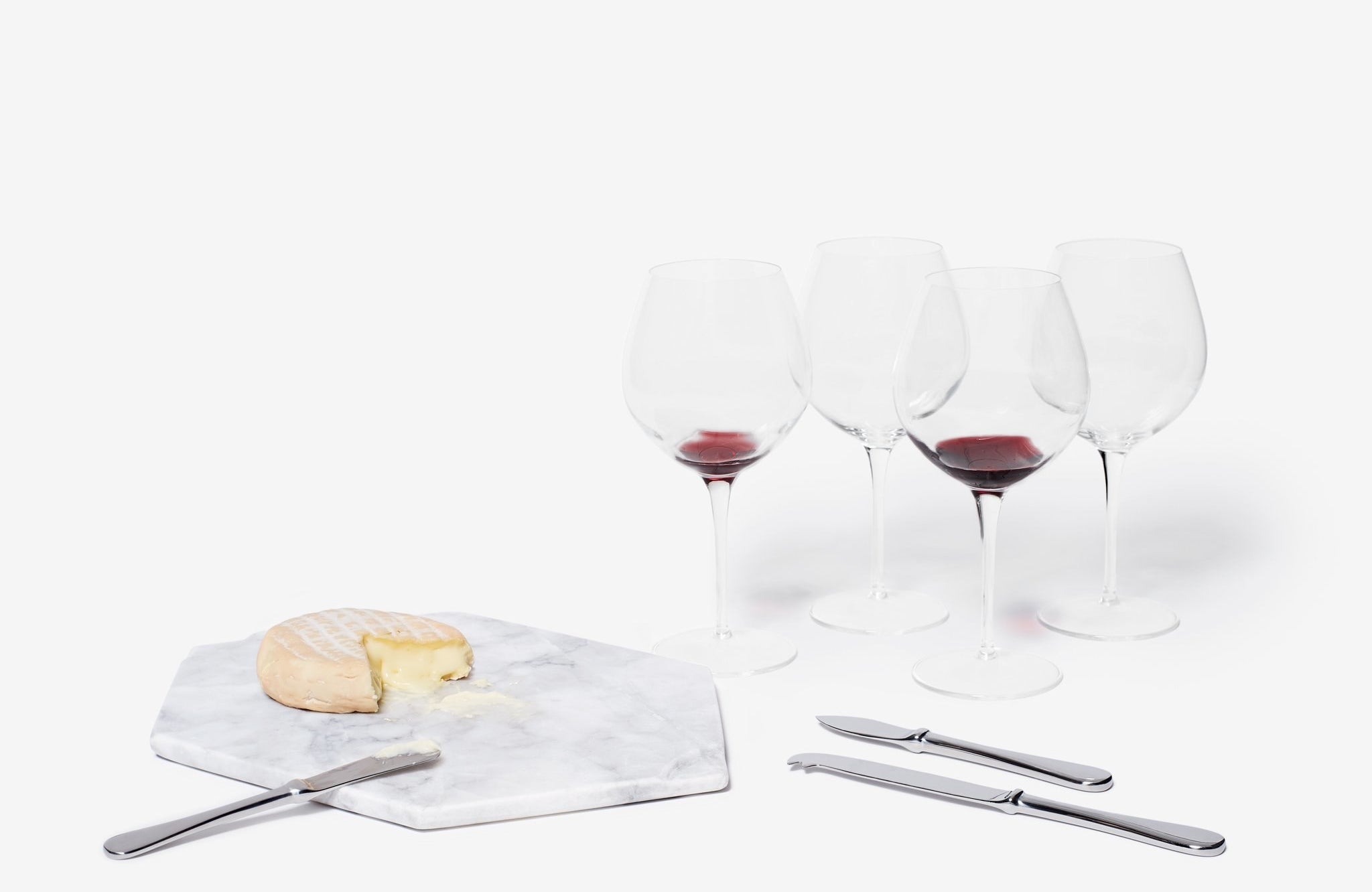 marble cheeseboard with brie wheel next to wine glasses