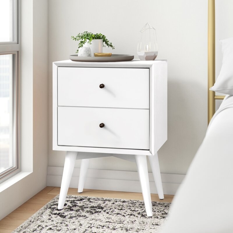 Double drawer white end table with dish, plant and vase on top