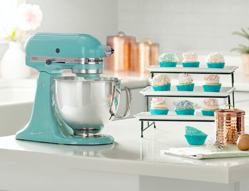 Turquoise kitchen aid stand mixer next to cupcakes on white counter