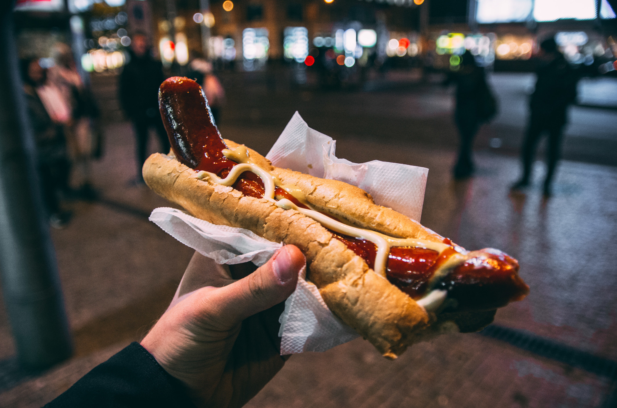 A hand holding a hotdog.