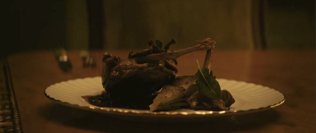 A plate with a cooked pigeon on it sitting on a table