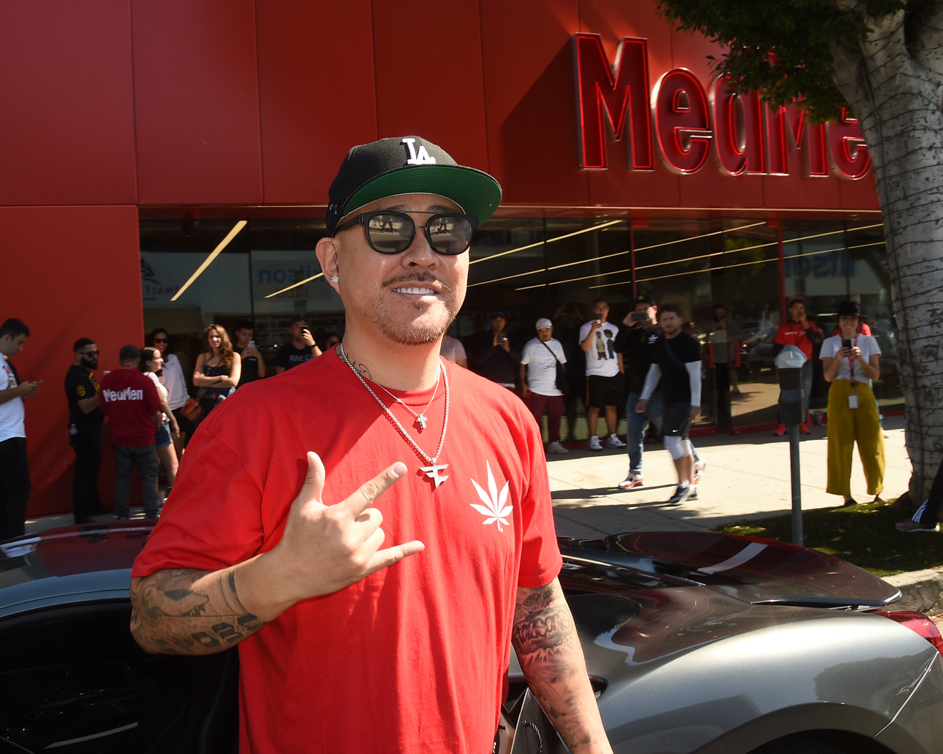 A guy giving the rock sign in front of MedMen dispensary
