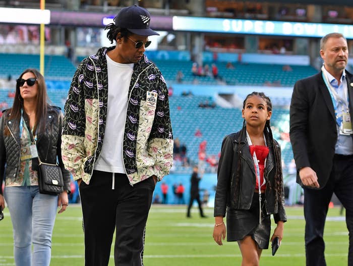 blue walks next to her dad at a football stadium