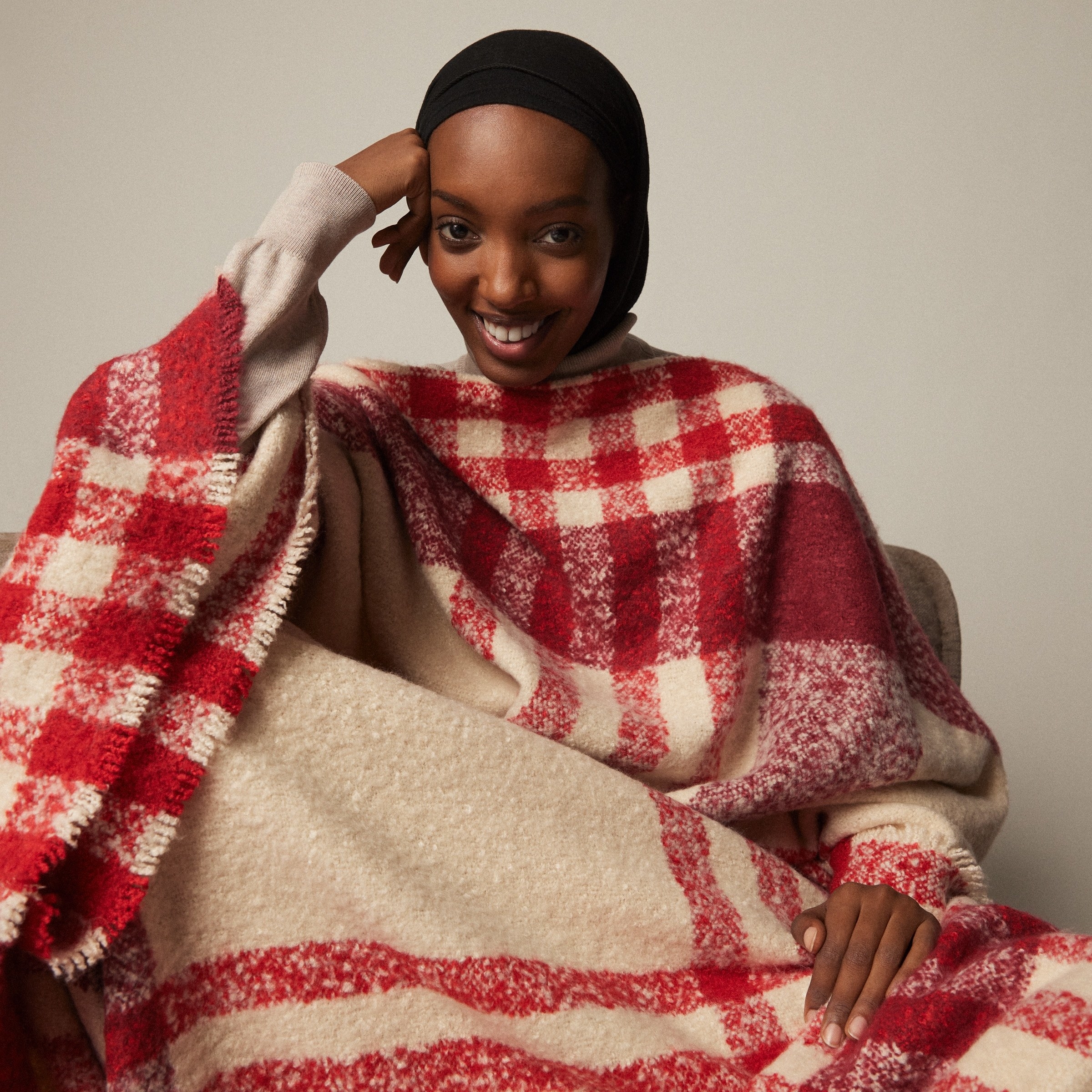 a smiling person wearing the wearable plaid blanket