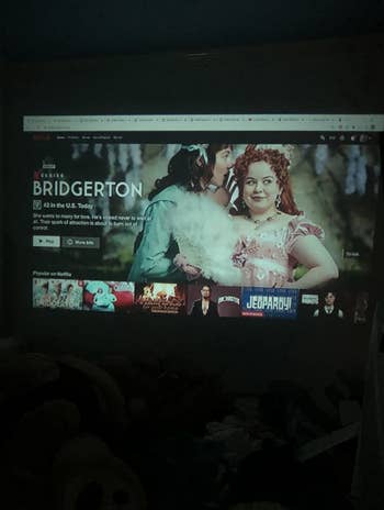 a reviewer shows the projector showing Netflix on their dorm room wall