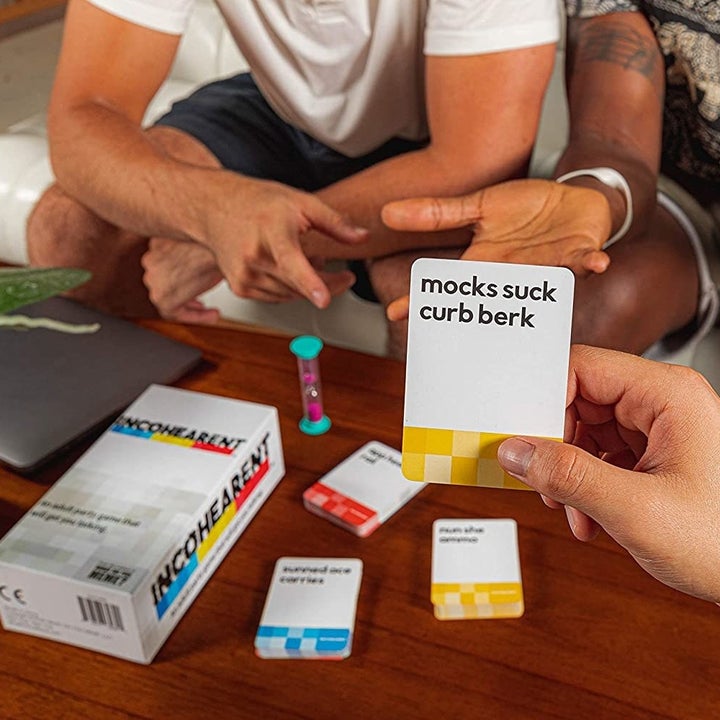 models playing the game and one holding a card the reads "mocks suck curb berk"