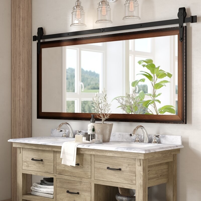 Large rectangular wooden vanity mirror over light wood double vanity