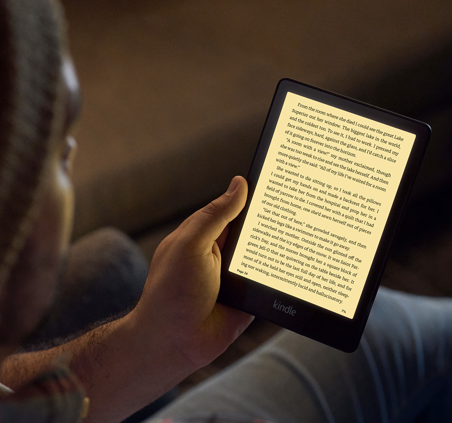 A person holding the Kindle illuminated with warm light