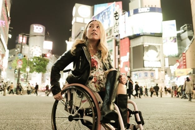 a young woman in a wheelchair in the middle of a busy tourist spot in a city