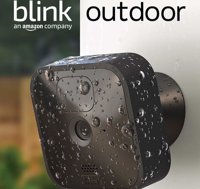 The camera on an outdoor wall covered in rain droplets