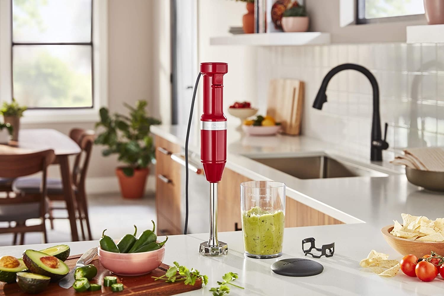 The blender next to a cup of guacamole on a counter