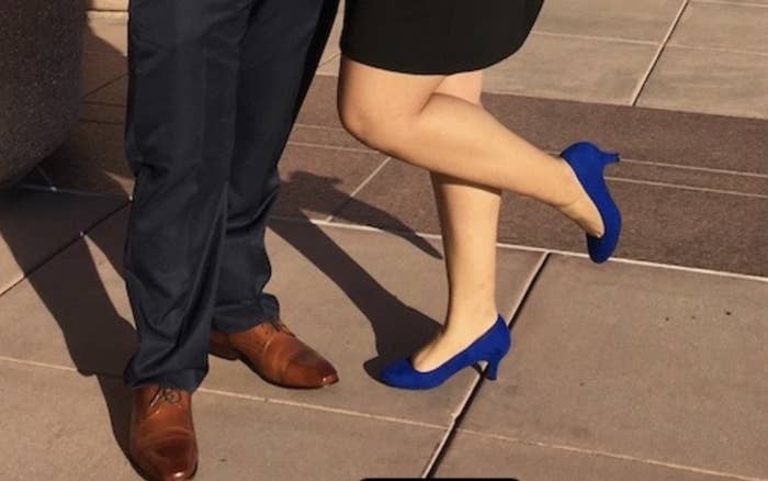 A reviewer's photo of herself wearing the royal blue heels standing next to her date in oxfords at a wedding