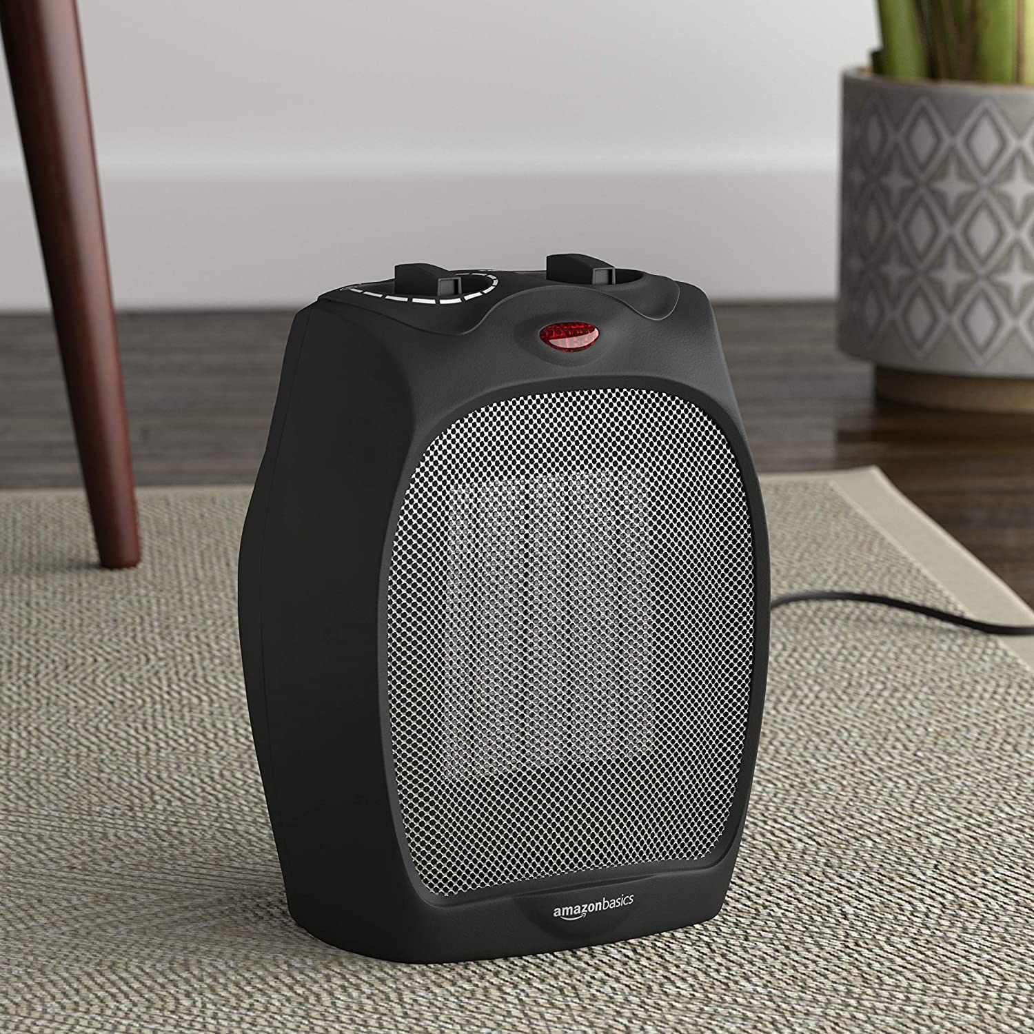 The space heater on a carpet with a plant and table leg in the background