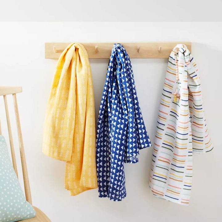 a yellow, blue, and white blanket with rainbow stripes handing on white hooks