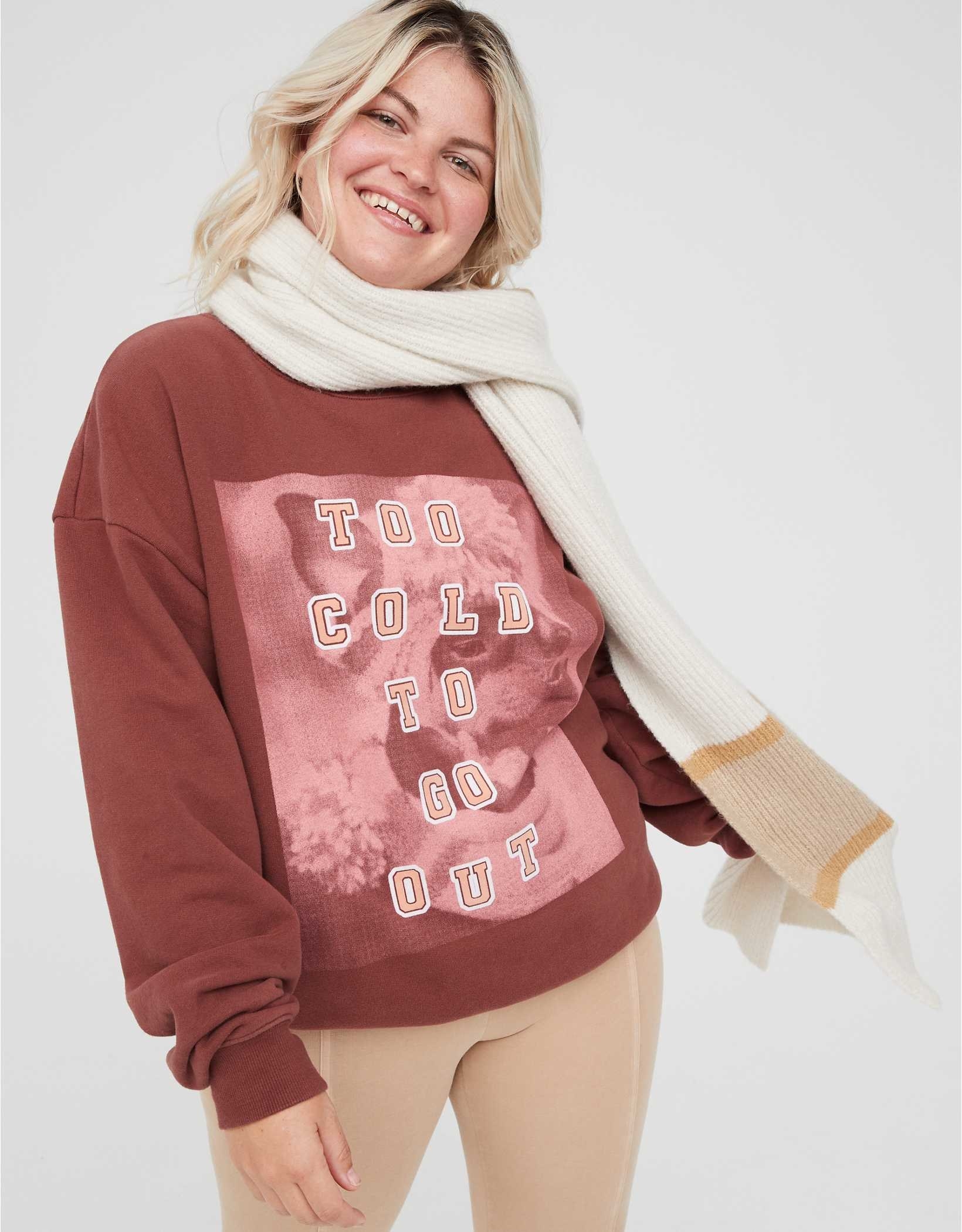 model wearing maroon sweatshirt with a picture of a dog wearing a hat and scarf and the words &quot;Too cold to go out&quot; printed over the image