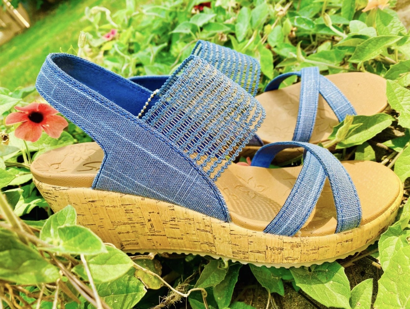 A reviewer&#x27;s photo of the blue wedge sandals in a garden bed