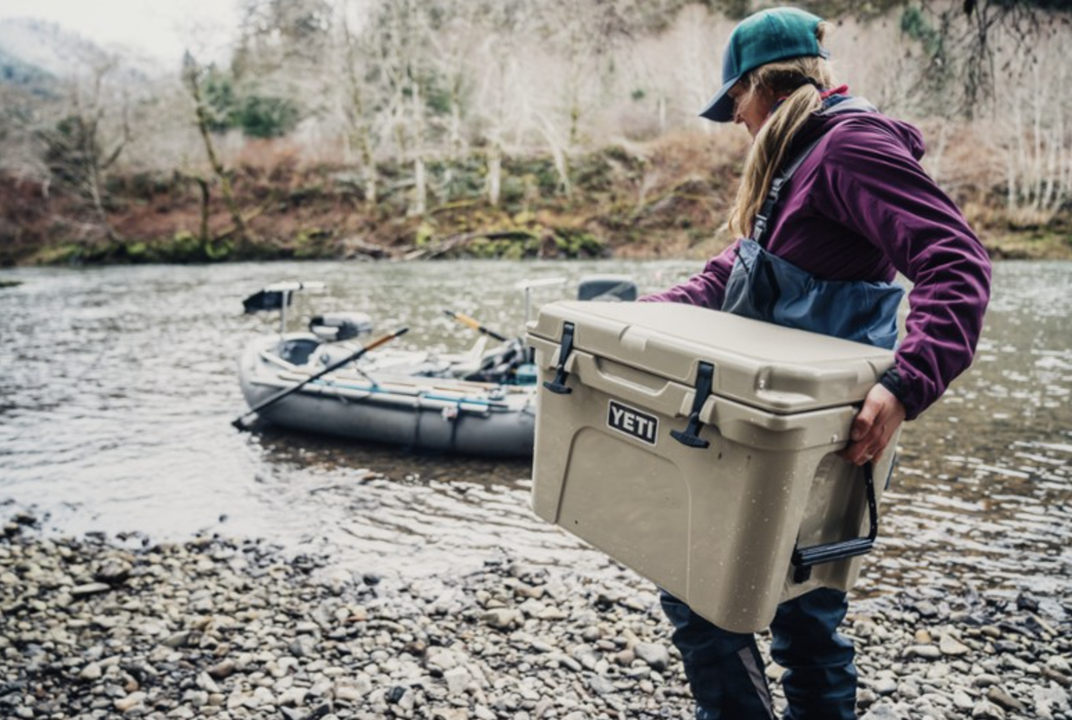 a model carrying a tan yeti cooler to a boat