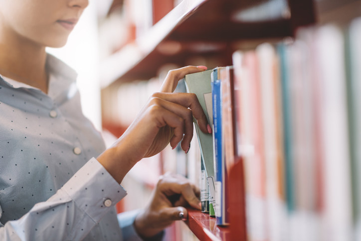 A librarian looking through a shelf of books