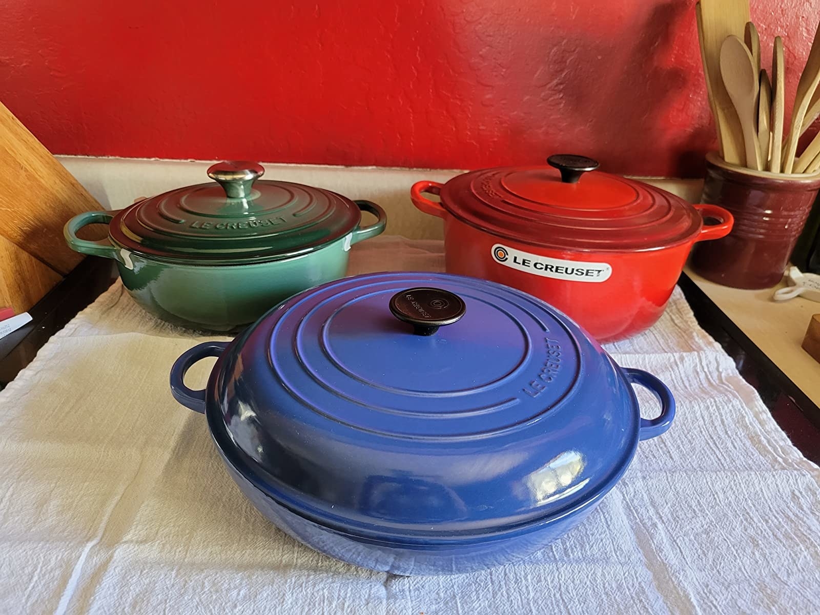 green, red, and blue Le Creuset pans on table