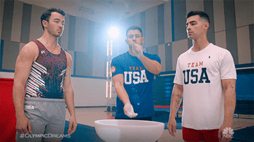 a gif of the jonas brothers in a gymnastics arena