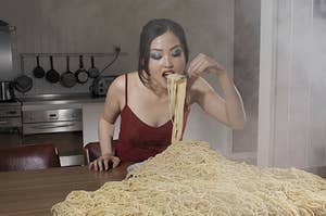 a woman eating a bunch of spaghetti off the table