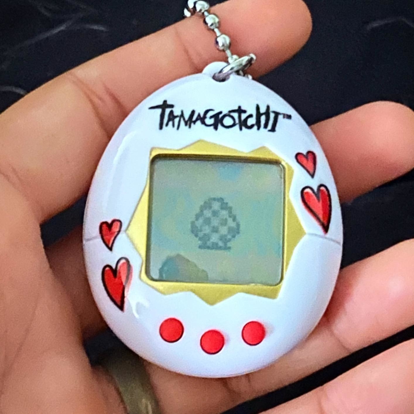 a reviewer&#x27;s white tamagotchi case with red hearts and red buttons