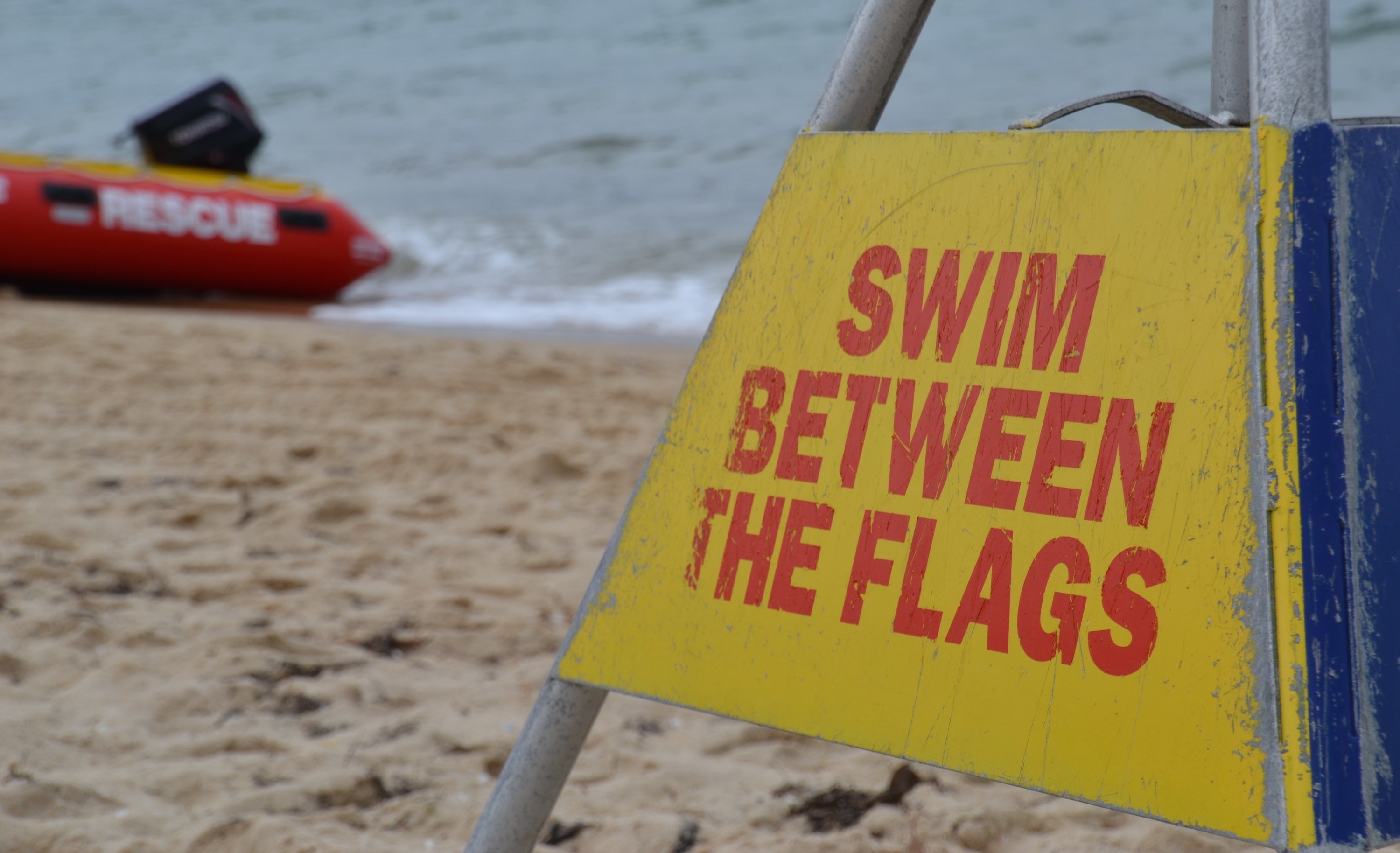 sign that reads, &quot;Swim between the flags,&quot; on a beach in Australia