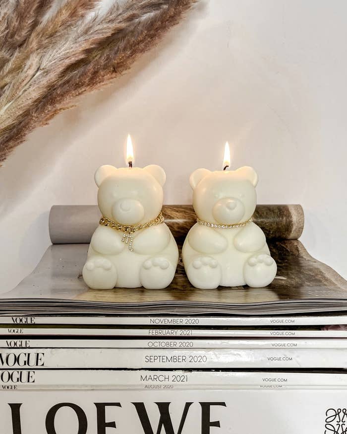 two candles shaped like bears sitting on top of a stack of magazines