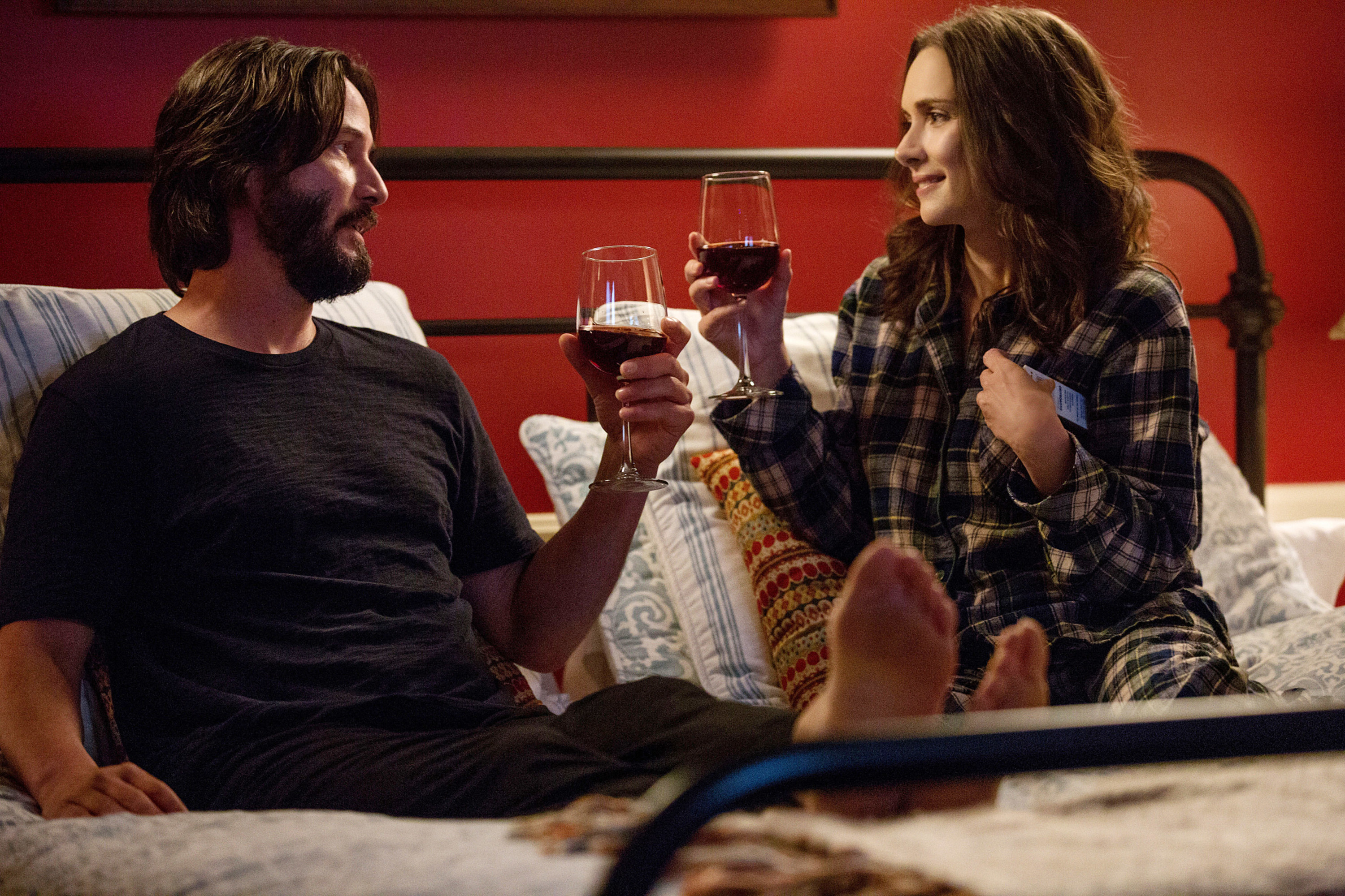 Keanu and Winona share a glass of wine in bed in the movie