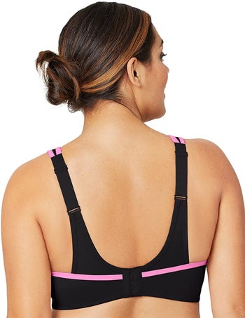 Back of model wearing black sports bra with pink trim