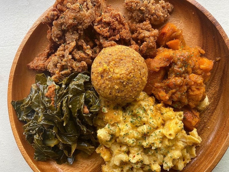 Photo of a fried oyster mushroom with vegan mac and cheese, collard greens, and sweet potatoes