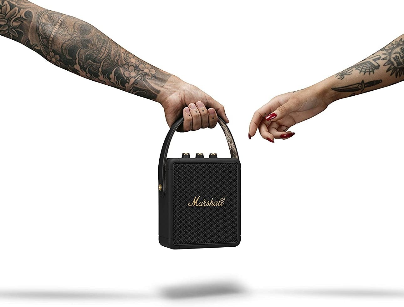 someone handing a person the bluetooth speaker by its top handle