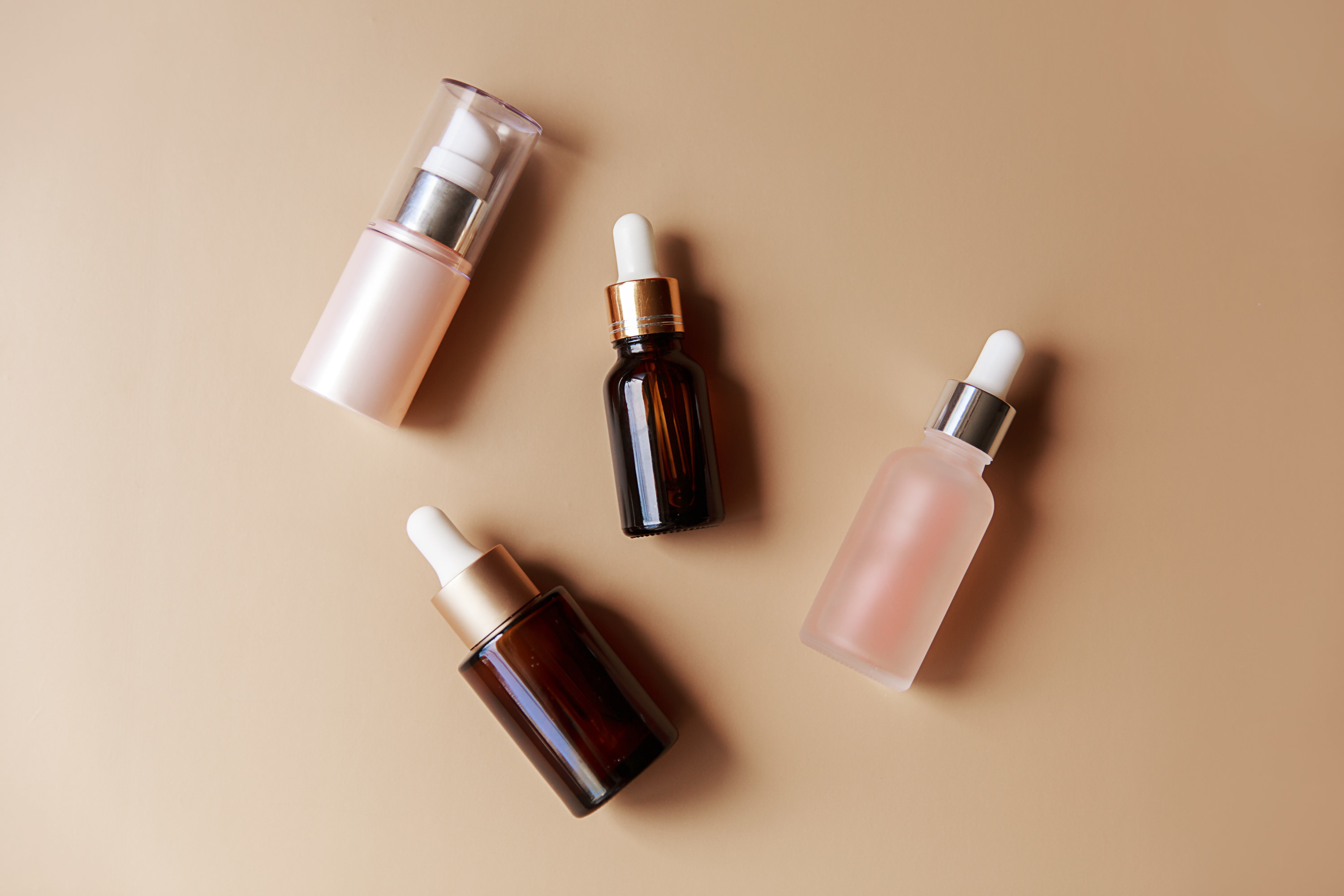 Cosmetic bottles laying against a beige background