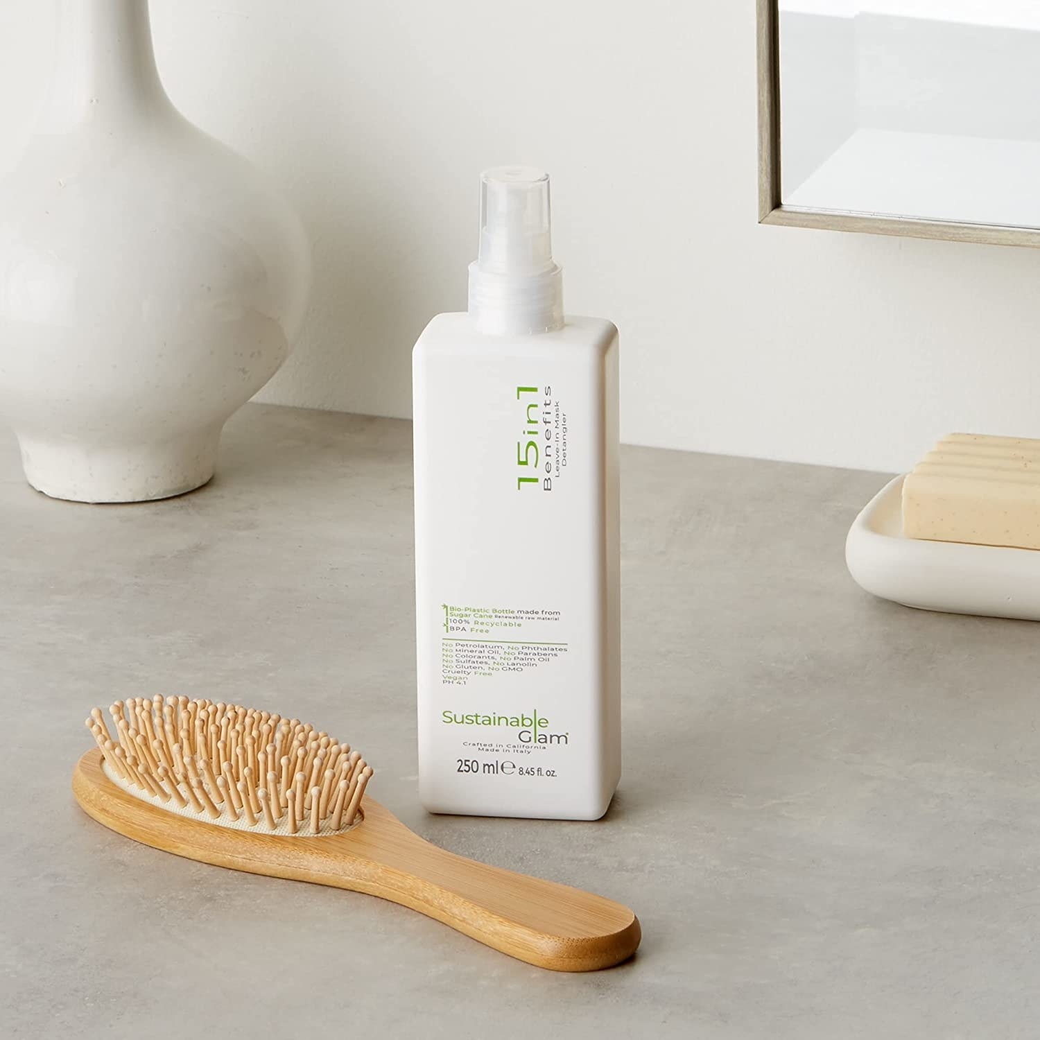 A bottle of Sustainable Glam leave-in conditioner set on a bathroom counter.