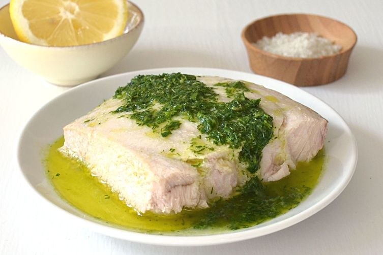 Baked fish topped with a green herb and lemon sauce.