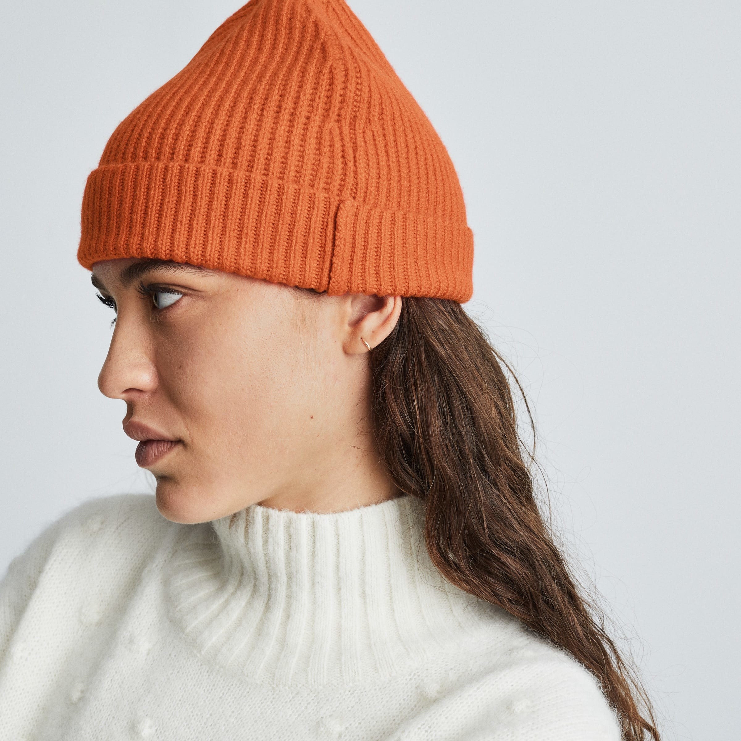 Model wearing the orange beanie with the cuff folded over