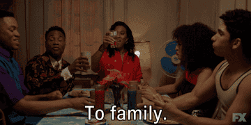 A group of people toasting at dinner and saying &quot;to family&quot;